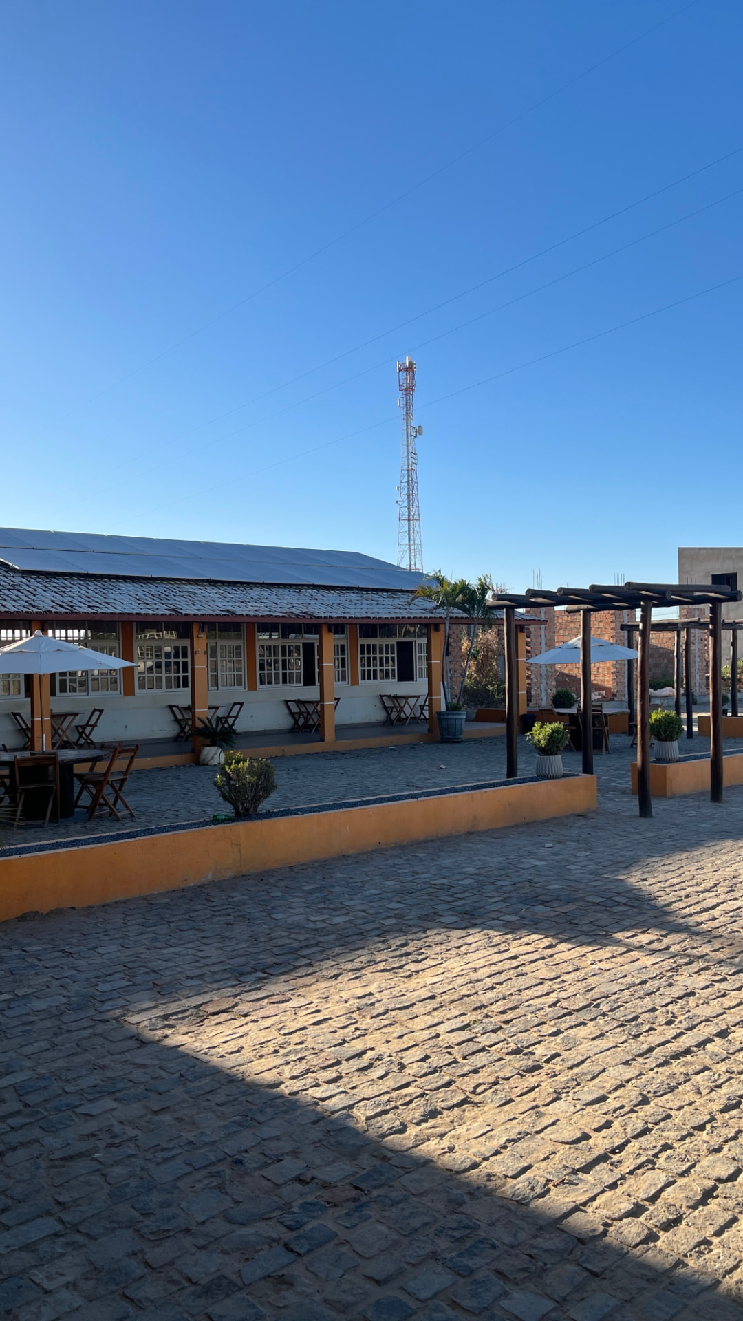 Pátio com pergolado, jardim e mesas na parte externa